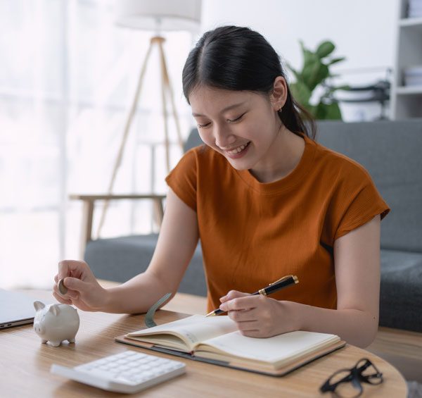 Image of a women writing in a notebook sitting at a table
